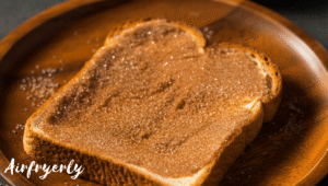 Cinnamon sugar topping sprinkled on buttered toast for Cinnamon Toast Air Fryer.
