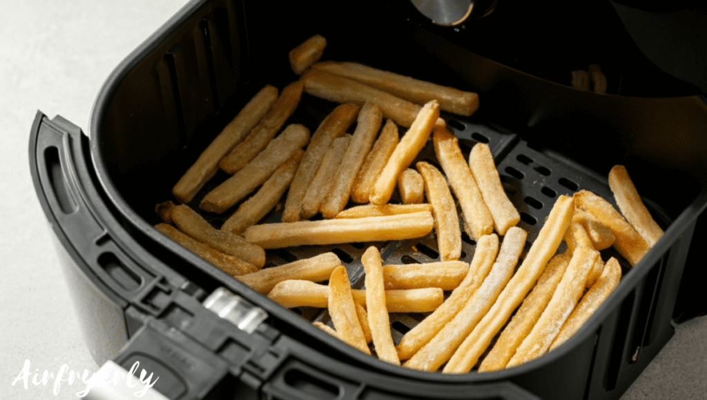 Fries cooking in the air fryer at 400°F. Some fries flipped. Golden edges starting to form.