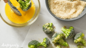 Broccoli florets being dipped in egg wash and coated in breadcrumb Parmesan mixture