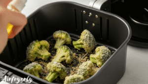 Breaded broccoli florets placed in a single layer inside the air fryer basket ready to cook