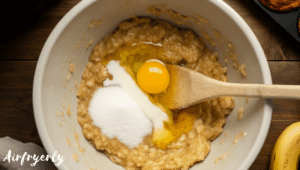 Mashed ripe bananas in a bowl mixed with egg, sugar, milk, and melted butter