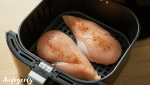 Raw chicken breasts placed in a single layer inside an air fryer basket, ready to cook at 390°F.