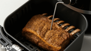 Seasoned lamb rack placed inside an air fryer basket bone-side down, ready to cook