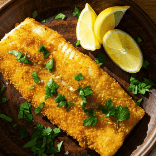 Crispy golden grouper fillets served with lemon wedges and herbs, cooked in air fryer
