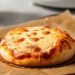 Frozen mini cheese pizza placed in air fryer basket before cooking, with even spacing and no parchment, ready for air frying.