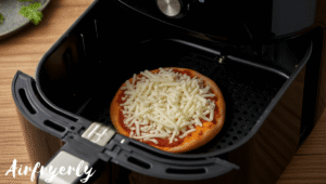 Mini frozen cheese pizza placed in air fryer basket with space around for proper airflow