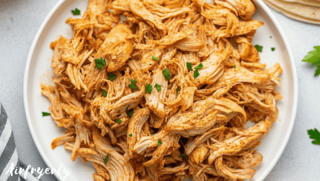 Freshly shredded chicken served in a bowl with herbs, ready to enjoy in tacos, salads, or rice bowls.