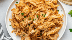 Freshly shredded chicken served in a bowl with herbs, ready to enjoy in tacos, salads, or rice bowls.