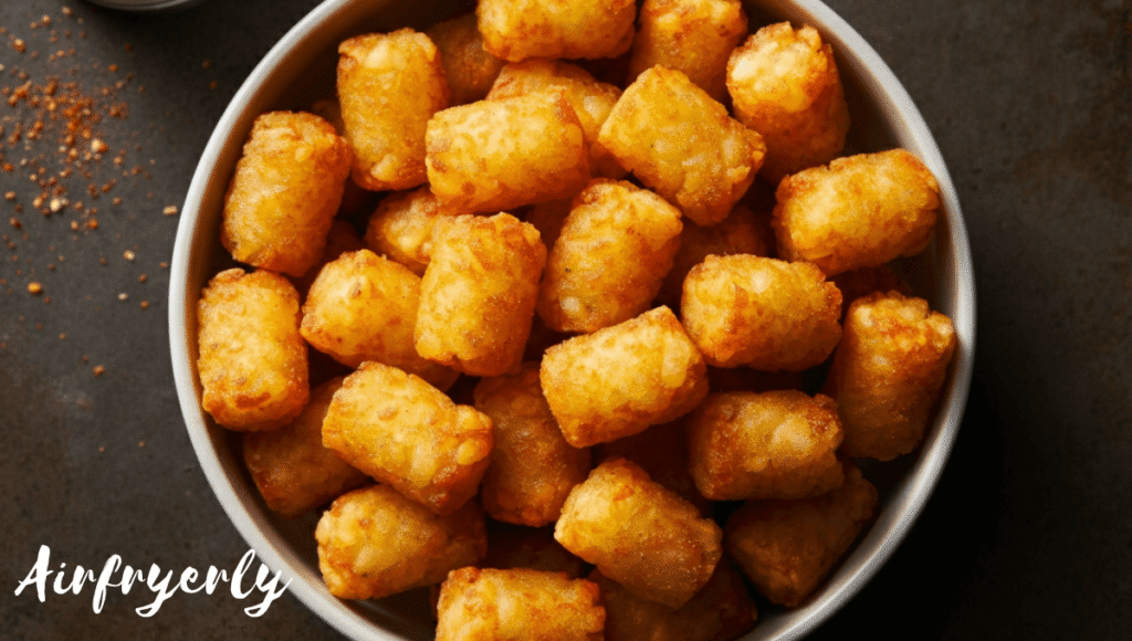 Golden crispy Ore Ida tater tots air fryer recipe served in a white bowl with dipping sauce on the side