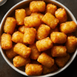 Golden crispy Ore Ida tater tots air fryer recipe served in a white bowl with dipping sauce on the side