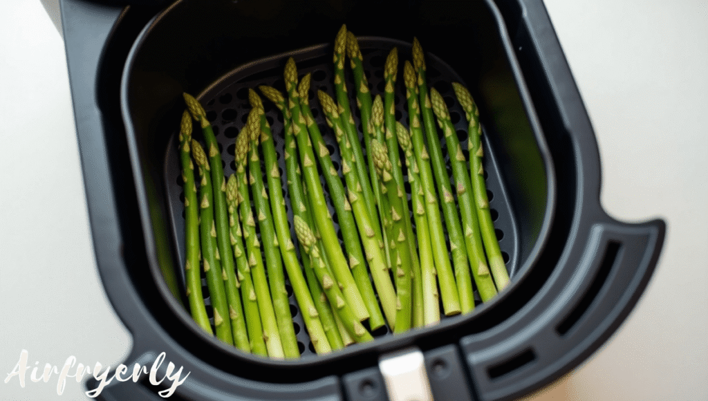 "Frozen asparagus spears arranged in a single layer in an air fryer basket before cooking."