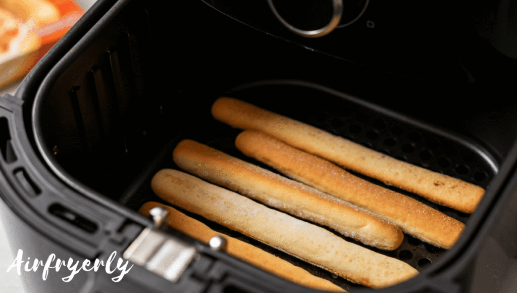 “Frozen New York Bakery breadsticks placed in a single layer inside an air fryer basket, ready to cook at 370°F.”