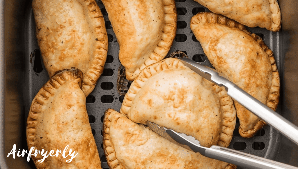 Air Fryer Frozen Empanadas cooking inside the air fryer basket, turning golden brown and crispy.