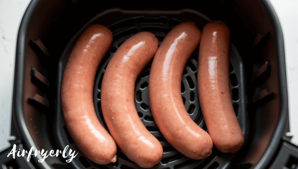 Brats arranged in a single layer inside air fryer basket to ensure even cooking and perfect crispiness.