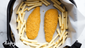 Chicken kievs placed in air fryer basket on paper liner with space between for even cooking